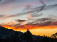 Rot leuchtender Wolkenstreifen über Aschauer Kirchtürme am Abend